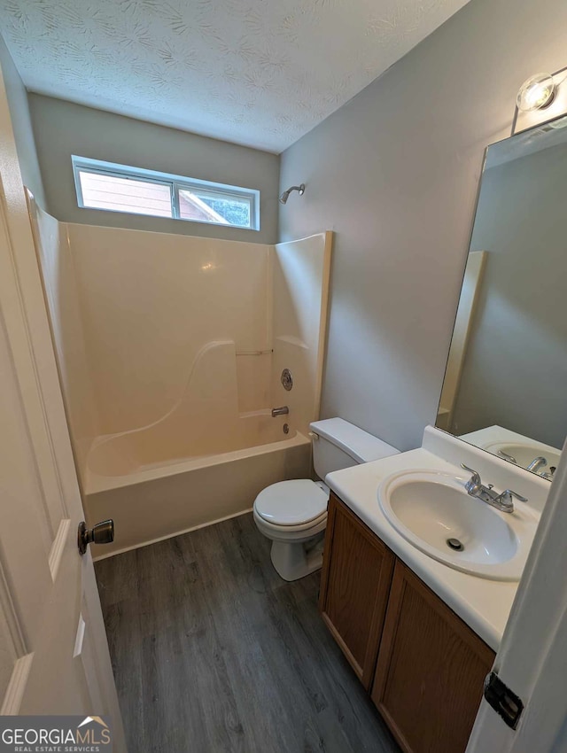 full bathroom featuring a textured ceiling, vanity, bathing tub / shower combination, hardwood / wood-style floors, and toilet