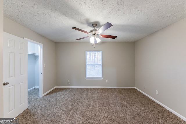 unfurnished bedroom featuring carpet flooring, ceiling fan, a spacious closet, and a textured ceiling