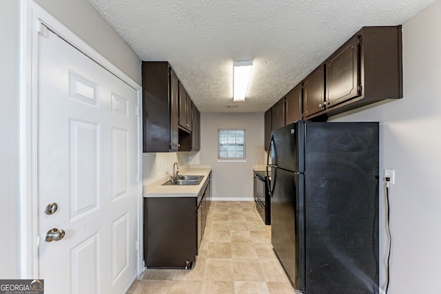 kitchen with dark brown cabinetry, black fridge, sink, and a textured ceiling