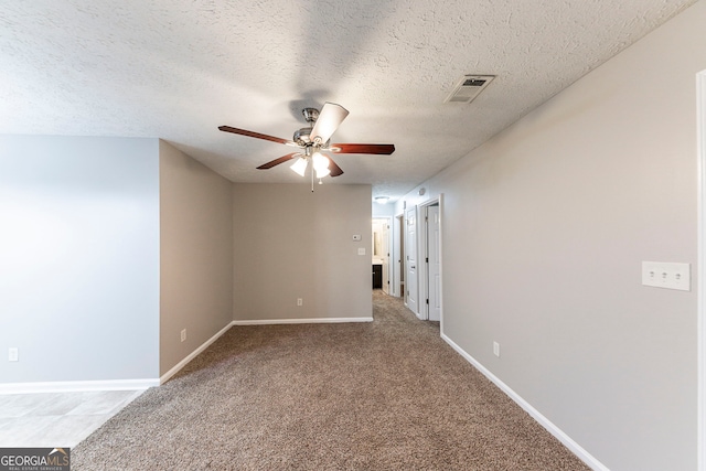 carpeted empty room featuring ceiling fan and a textured ceiling