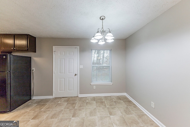 unfurnished dining area with a notable chandelier and a textured ceiling