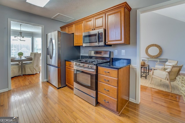 1103 Etowah Valley Ln, Woodstock, GA 30189 - kitchen with light wood-type flooring, a textured ceiling, appliances with stainless steel finishes, and an inviting chandelier