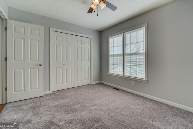 1103 Etowah Valley Ln, Woodstock, GA 30189 - unfurnished bedroom featuring a textured ceiling, ceiling fan, light carpet, and a closet