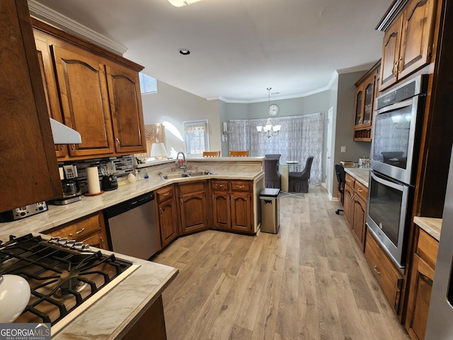 kitchen featuring stainless steel appliances, sink, decorative light fixtures, light hardwood / wood-style flooring, and a chandelier