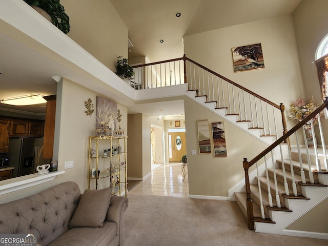 carpeted foyer entrance with a towering ceiling