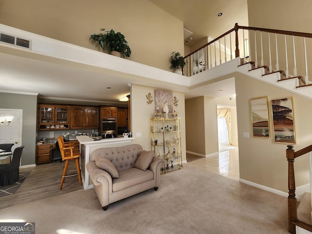 living room with light wood-type flooring, a towering ceiling, and ornamental molding