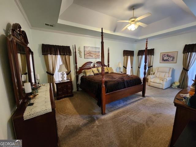 carpeted bedroom with ceiling fan, ornamental molding, and a tray ceiling