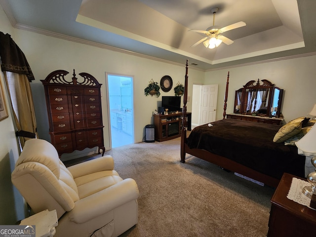 bedroom with a raised ceiling, connected bathroom, ceiling fan, and carpet floors