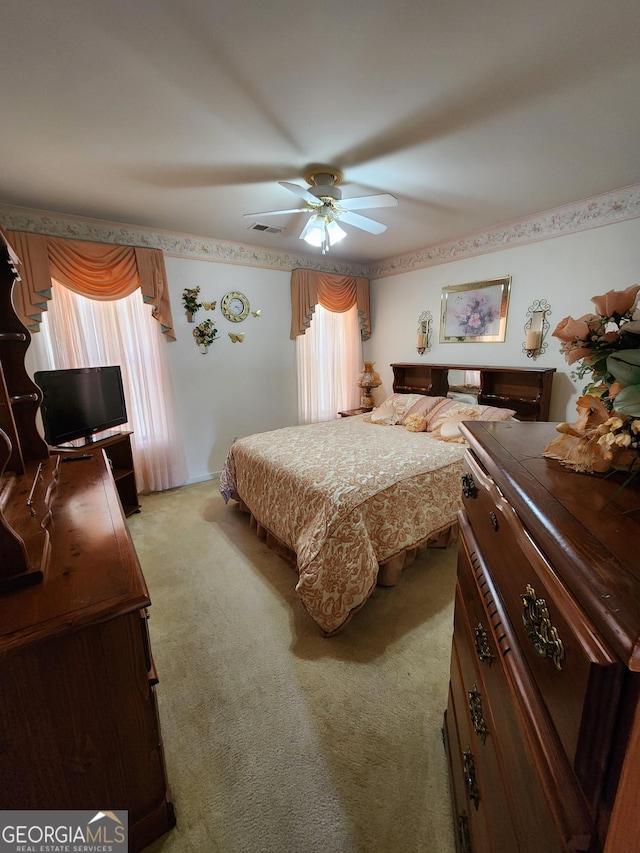 bedroom with ceiling fan, light carpet, and multiple windows