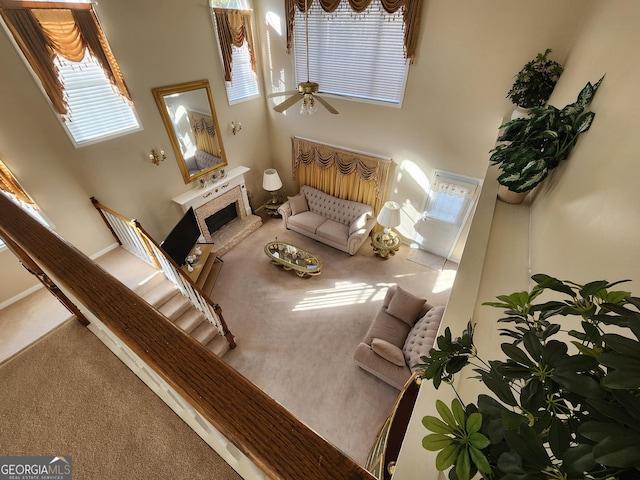 living room featuring carpet, ceiling fan, and a towering ceiling