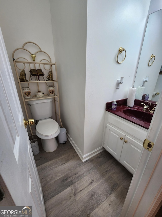 bathroom with hardwood / wood-style floors, vanity, and toilet