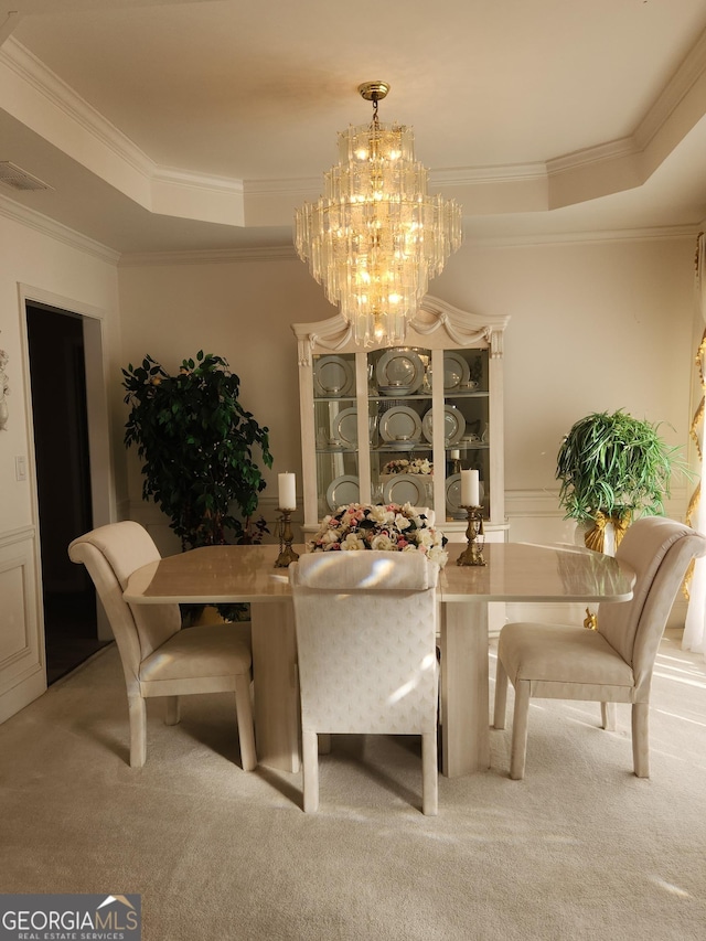 carpeted dining room with a notable chandelier, ornamental molding, and a tray ceiling