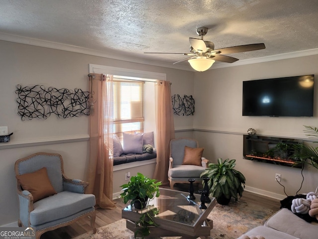 living room featuring wood-type flooring, a textured ceiling, ceiling fan, and crown molding