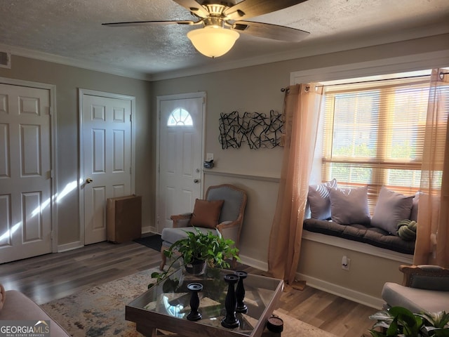 living room with ceiling fan, wood-type flooring, ornamental molding, and a textured ceiling