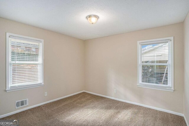 carpeted empty room with a textured ceiling