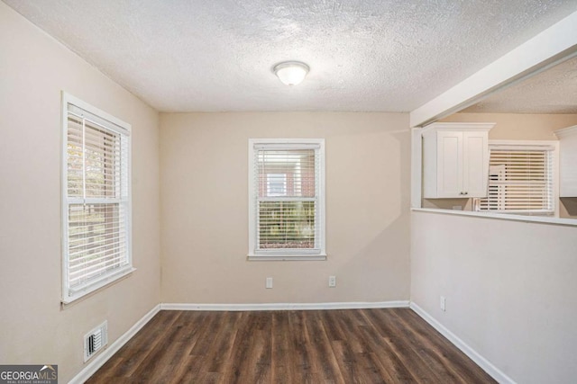 unfurnished room featuring dark hardwood / wood-style flooring and a textured ceiling