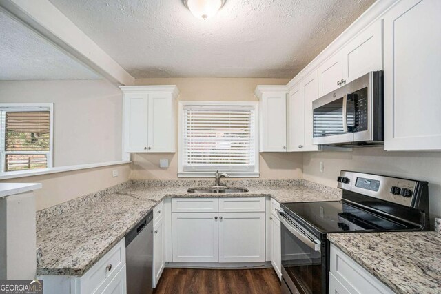 kitchen with white cabinetry, sink, dark hardwood / wood-style flooring, a textured ceiling, and appliances with stainless steel finishes