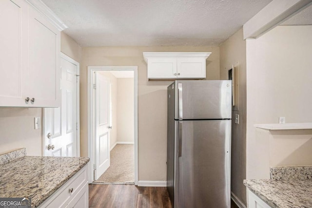 kitchen featuring white cabinets, stainless steel fridge, dark hardwood / wood-style flooring, and light stone counters