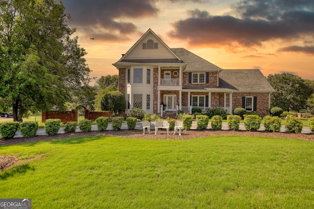 view of front facade with a lawn and a balcony