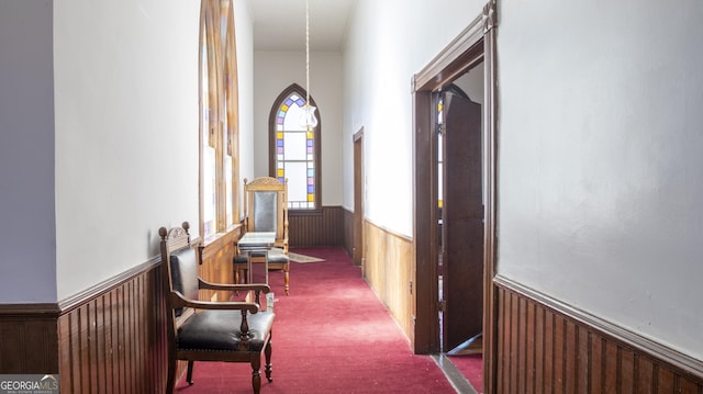 hallway featuring dark colored carpet and wooden walls