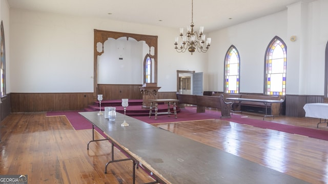 dining space featuring hardwood / wood-style flooring, an inviting chandelier, and wood walls