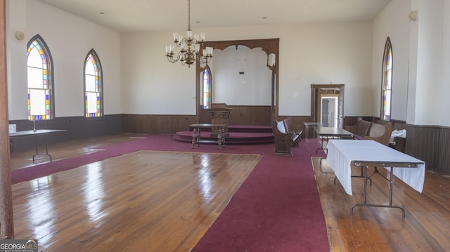 living room with a chandelier, dark wood-type flooring, and wood walls