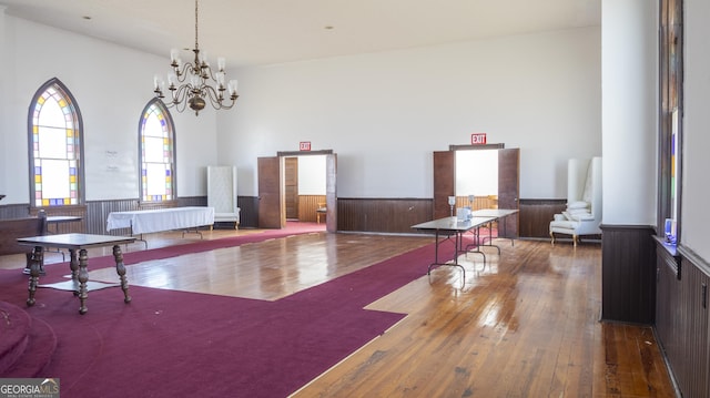 miscellaneous room with a notable chandelier, wood walls, and wood-type flooring