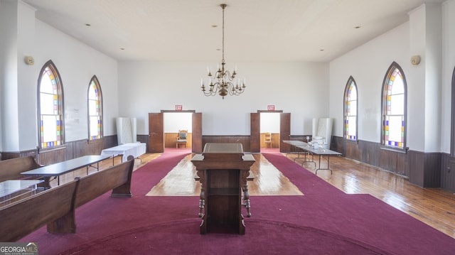 dining room featuring wooden walls, a chandelier, and wood-type flooring