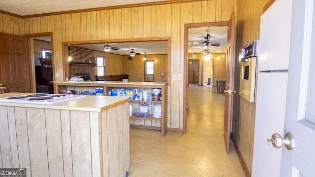 kitchen featuring ornamental molding, oven, wooden walls, and white gas stovetop