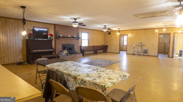 dining area featuring a wood stove, wood walls, ceiling fan, and a textured ceiling