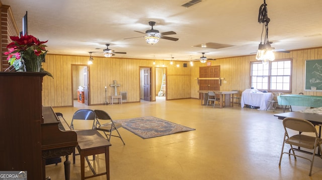 living room featuring wood walls and ceiling fan