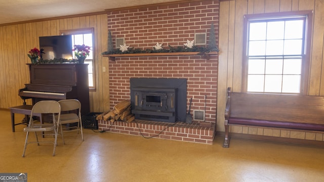 living room featuring a wood stove, a wealth of natural light, wooden walls, and crown molding