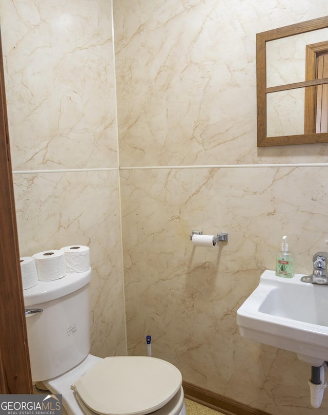 bathroom with sink, toilet, and tile walls