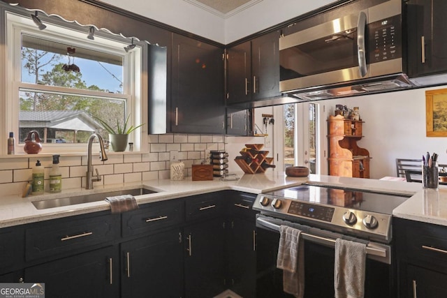 kitchen featuring backsplash, crown molding, sink, light stone counters, and stainless steel appliances