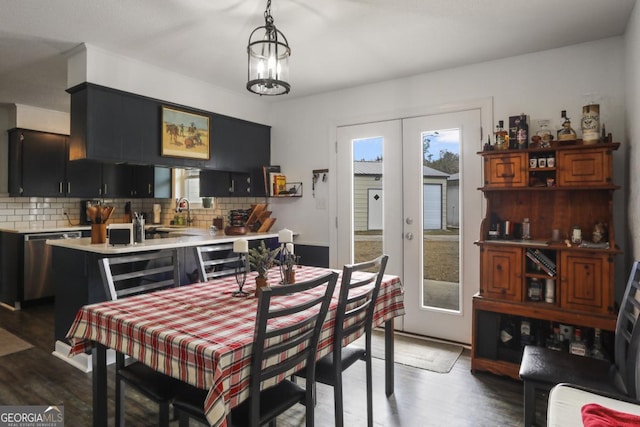 dining space with french doors, dark hardwood / wood-style flooring, an inviting chandelier, and sink