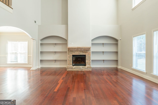 unfurnished living room with built in shelves, a fireplace, and hardwood / wood-style floors