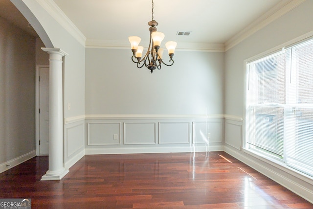 unfurnished dining area featuring crown molding, dark hardwood / wood-style flooring, a chandelier, and ornate columns