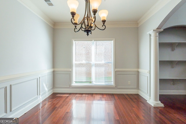 unfurnished dining area with crown molding, dark hardwood / wood-style flooring, a chandelier, and ornate columns