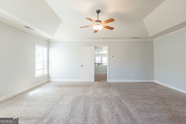 carpeted empty room featuring a raised ceiling, crown molding, and ceiling fan