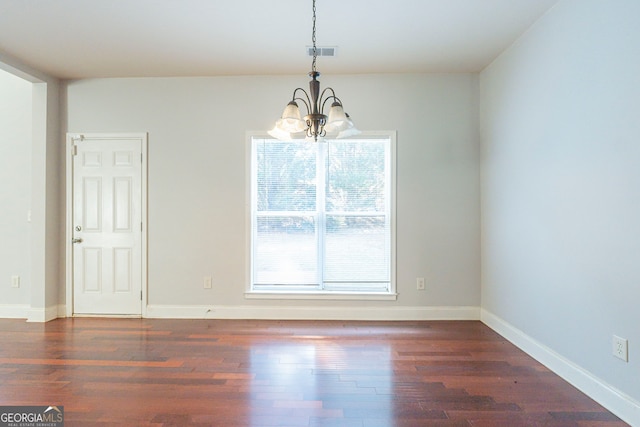 spare room featuring dark hardwood / wood-style floors and an inviting chandelier