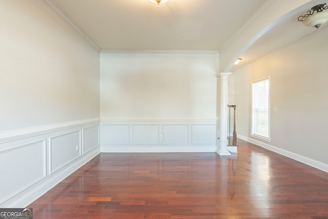 spare room with crown molding, dark hardwood / wood-style flooring, and ornate columns