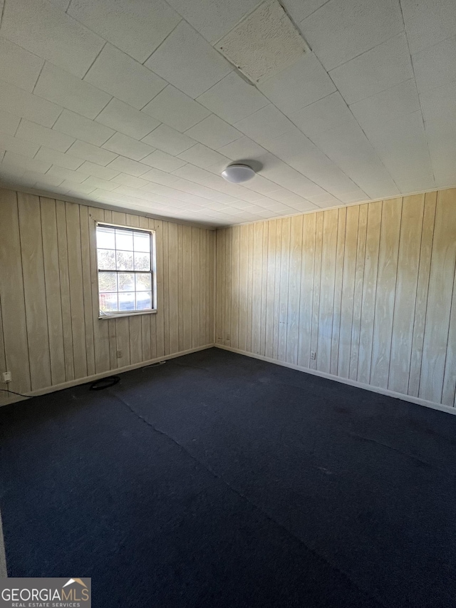 empty room featuring carpet flooring and wood walls