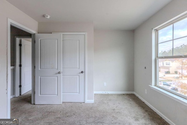 unfurnished bedroom featuring light carpet and a closet