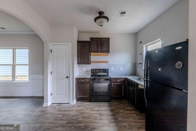 kitchen featuring black appliances, dark hardwood / wood-style floors, light stone counters, and tasteful backsplash