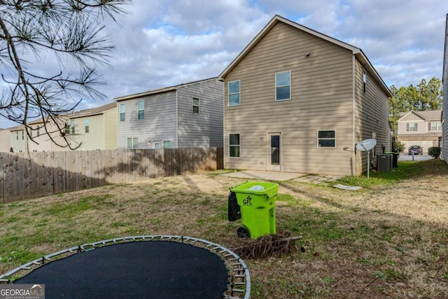 rear view of house featuring a yard, a trampoline, and cooling unit