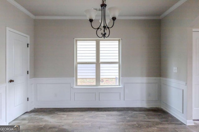 spare room featuring an inviting chandelier, ornamental molding, and hardwood / wood-style flooring