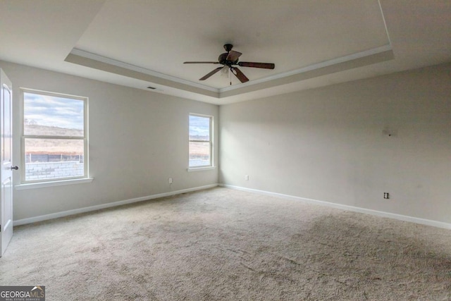 carpeted empty room featuring a raised ceiling, crown molding, and ceiling fan