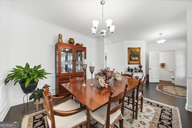 dining area with ornamental molding, dark wood-type flooring, and an inviting chandelier