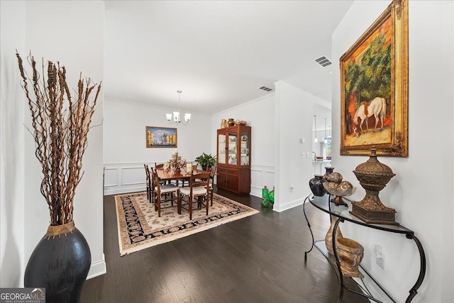 dining area featuring crown molding, dark hardwood / wood-style flooring, and an inviting chandelier