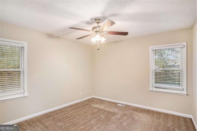 carpeted empty room featuring ceiling fan and a textured ceiling